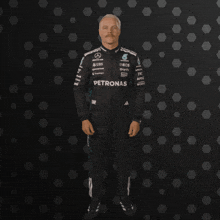 a man in a petronas uniform holds his fist in the air