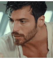 a close up of a man 's face with a beard wearing a white shirt