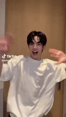 a young man in a white shirt is making a funny face with his mouth open .