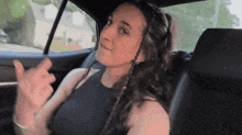 a woman is sitting in the back seat of a car and giving the middle finger