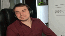 a man wearing headphones is sitting in front of a white board with a green avocado in the background