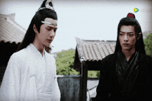two men are standing next to each other and one of them is wearing a feathered headpiece