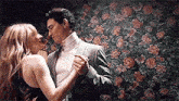 a man and a woman are dancing together in front of a floral wallpaper .