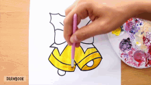 a person is painting a bell with a pink brush