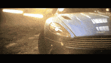 a close up of a car 's headlight with the word aston martin on it