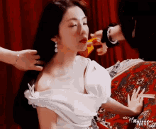 a woman in a white dress is sitting on a red couch with her eyes closed