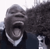 a man is yawning with his mouth wide open in a black and white photo .