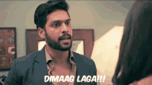 a man in a suit says " dimaag laga !!! " in front of a woman