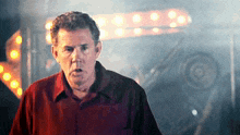 a man in a red shirt is standing in front of a carnival sign