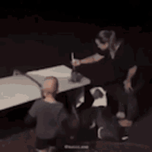 a person is standing next to a table in a dark room .
