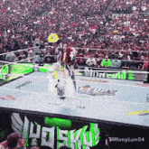a woman stands in a wrestling ring in front of a crowd with tiffanyluv24 written on the bottom right