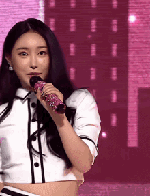a woman in a white shirt is singing into a microphone