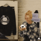 a woman in a plaid shirt is holding a panda stuffed animal