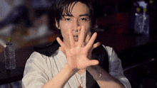 a young man in a white shirt is making a stop gesture with his hands