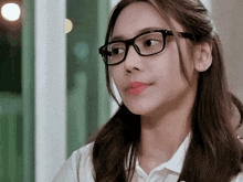 a woman wearing glasses and a white shirt looks at something