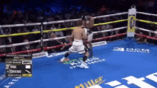 a boxing match is being played in a boxing ring with a miller lite advertisement on the floor .
