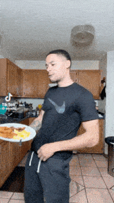 a man in a black nike shirt holds a plate of food