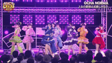 a group of girls are performing in front of a crowd with ocha norma written on the screen behind them