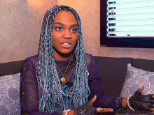 a woman with blue braids sitting on a couch