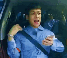 a man in a blue shirt is sitting in the back seat of a car .