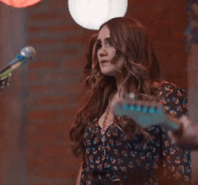 a woman is singing into a microphone while holding a guitar .
