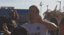 a man in a white shirt that says leone is dancing in a crowd .