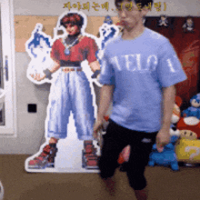 a man wearing a blue shirt that says " welcome " stands in front of a cardboard cutout of a boy