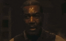 a man with blood on his face is standing in the dark .