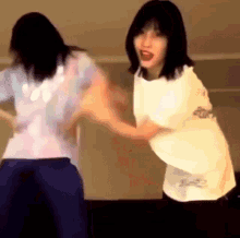 two women are standing next to each other holding hands and dancing .