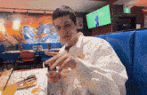 a man in a white shirt sits at a table in a diner