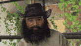 a man with long hair and a beard wearing a black cowboy hat
