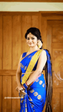 a woman wearing a blue saree with a yellow sash