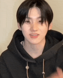 a close up of a person wearing a black hoodie and earrings .