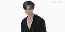 a young man wearing a black shirt and a necklace is smiling on a white background .