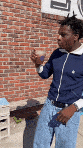 a man standing in front of a brick wall holding a cup in his hand