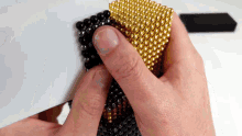 a person is holding a cube of black and gold balls