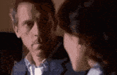 a man and a woman are sitting next to each other and looking at each other .