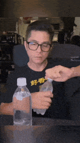 a man wearing glasses is holding a bottle of water with chinese writing on it