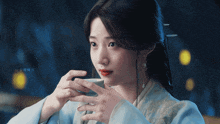 a woman in a blue jacket is holding a white cup in her hand