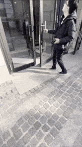 a man with a backpack is opening a door on a cobblestone sidewalk