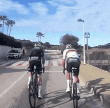 two cyclists are riding down a road with a sign that says " atencion "