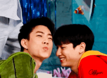 a couple of boys are kissing each other and one of them is wearing a red shirt that says offgun
