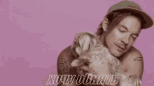 a shirtless man is holding a small white dog in his arms .