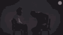 a man in a black shirt is standing next to a woman in a chair with ios written on the bottom of the screen