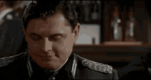 a man in a military uniform is sitting at a bar talking to a man in a suit .