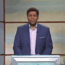 a man in a blue suit stands in front of a podium that says snl on it