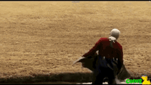 a man in a red jacket is walking across a grassy field with the word grapz on the bottom right