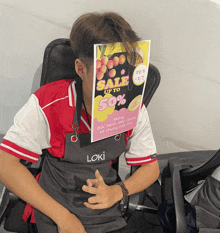 a man covering his face with a sign that says sale up to 50 % on it