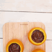 a wooden cutting board with sliced oranges and chocolate