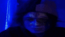 a person 's face is shown in a dark room with a blue light behind them
